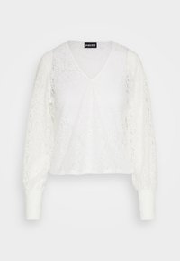 Blusa bianca in pizzo con scollo a V, maniche lunghe e polsini arricciati. Motivo floreale su tutta la superficie, texture leggera e design cropped.