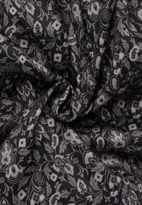 Schwarzer Stoff mit floralem und Paisleymuster in Grautönen. Die Textur wirkt weich und glatt mit filigranen Details.