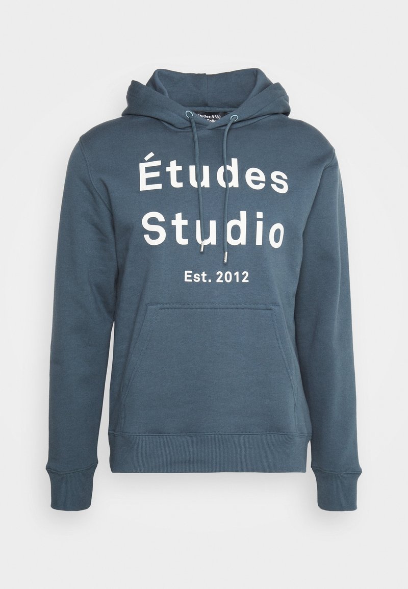 Sweat à capuche bleu avec poche kangourou et texte blanc "Études Studio Est. 2012" sur la poitrine.