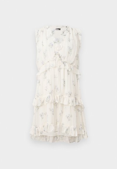 Blomstrete kjole i lys krem, med volanger på ermet og lagdelt design. Justerbar knyte-detalj foran gir en mykhet.