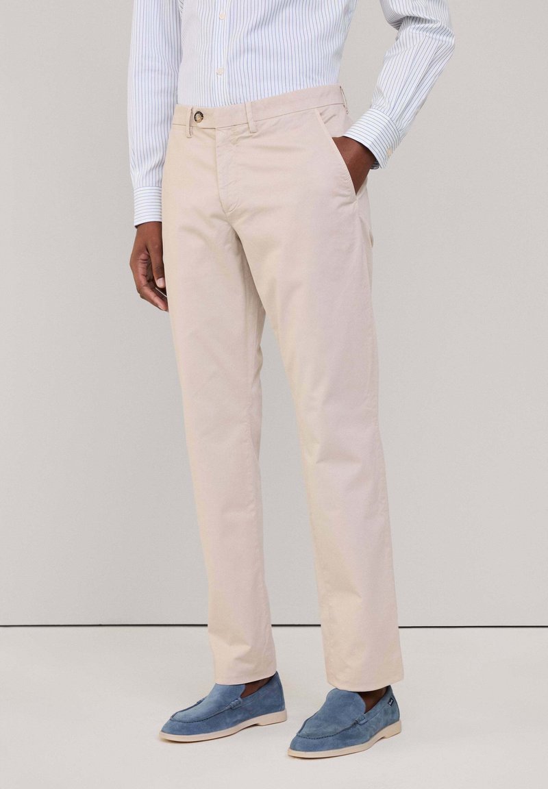 Chino beige in twill di cotone, con vestibilità standard, tasche laterali e chiusura con un singolo bottone in vita.