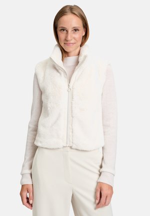 Witte nepbonten vest met een hoge kraag, ritsluiting en een recht model. Draag het over een lichte trui, gecombineerd met crèmekleurige broeken.