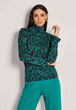 Hoge hals, lang mouwtop in turquoise en zwart dierenprint, gemaakt van zachte stof. Gecombineerd met bijpassende teal broek.