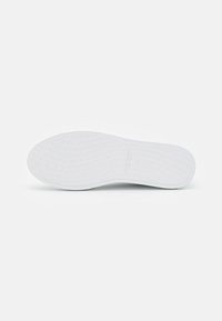 Semelle de sneaker blanche avec une surface texturée, présentant un motif en losanges et des bords lisses. Fabriquée en caoutchouc, conçue pour l'adhérence et le confort.