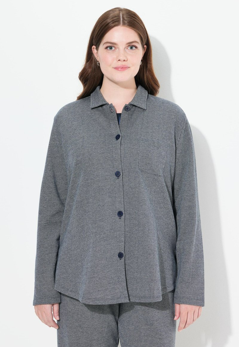 Camisa de botón de patrón de espiga gris con cuello, que cuenta con mangas largas y un bolsillo en el pecho, hecha de material texturizado.