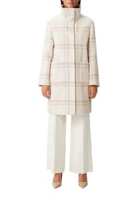Cappotto in misto lana di colore rosa chiaro con motivo a quadri, colletto alto, maniche lunghe e tasche laterali, abbinato a pantaloni bianchi a gamba larga.