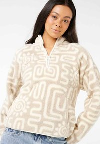 Fleece pullover i lys beige med moderne bølge- og geometriske mønstre, med halv-lynlås foran, stående krave og frontlomme.