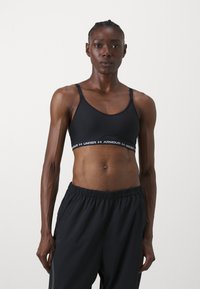 Juodas sportinis liemenukas, pagamintas iš lygios medžiagos, su apvalia iškirpte ir reguliuojamomis petnešomis. Ant juostos matoma "Under Armour" logotipas.