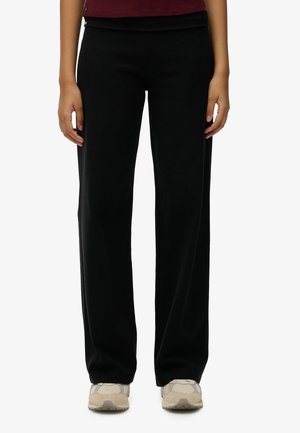 Pantalons larges noirs en tissu doux et extensible avec une texture lisse. Dotés d'une taille confortable et d'un design épuré.