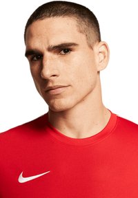 Rotes Sportshirt mit runder Ausschnitt und kurzen Ärmeln. Verfügt über ein weißes Nike-Logo auf der linken Brustseite. Glatte Textur.
