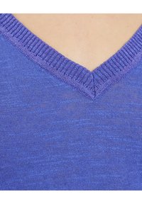 V-neck sweater in a medium purple shade, made of lightweight material. The neckline features a ribbed trim. Soft texture with a slight sheen.