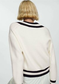 Crème ribbed trui met een relaxte fit, voorzien van een zwart-wit gestreepte kraag en manchetten. Zachte textuur met gebreide patroondetails.