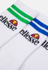Fehér bokazokni zöld és kék csíkokkal a tetején, fekete "ellesse" logóval és színes emblémával mindkét zoknin.