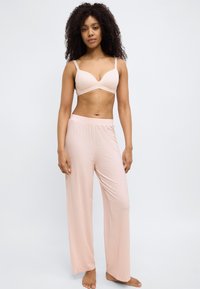 Light pink bralette with thin straps and matching palazzo pants featuring a subtle dot pattern. Soft, lightweight fabric. Casual design.