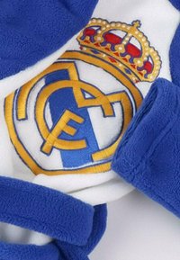 Niebieski szlafrok z polaru z logo Real Madryt. Logo zawiera żółte i białe detale oraz złotą koronę na szczycie.