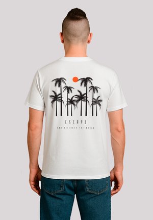 Weißes Baumwoll-T-Shirt mit einem graﬁschen Motiv von schwarzen Palmen und einer orangefarbenen Sonne, mit dem Text "ENTSPANNT DIE WELT ENTDECKEN" darunter.