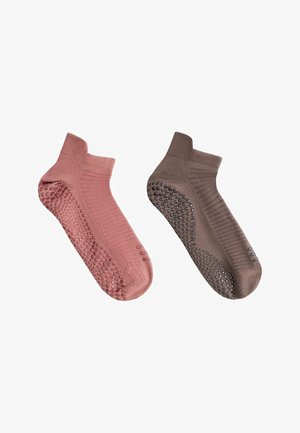 Paar knöchellange rutschfeste Socken, eine pink und eine braun, jeweils mit Gummipunkten an Sohle und Zehen.