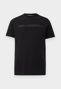 Črn bombažni T-majica s kratkimi rokavi, ki na sprednji strani ponuja dvignjen logo "KARL LAGERFELD". Okrogla izrezana ovratnica z gladko teksturo.