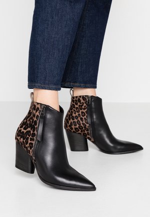 Schwarze Leder-Stiefeletten mit spitzen Zehen, Leopardenmuster-Akzenten und seitlichen Reißverschlüssen. Blockabsätze bieten Stabilität und Höhe.