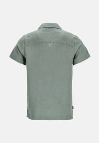 Camicia a maniche corte con colletto di colore verde chiaro, realizzata in tessuto strutturato con un aspetto leggermente stropicciato. Presenta un'etichetta sul lato.