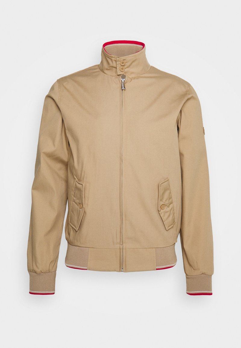 Veste beige zippée avec col montant et deux poches à rabat avec boutons, poignets et ourlet côtelés avec bordure rouge, présentée sur fond blanc.