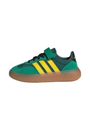 Groene en gele sneakers met een bovenwerk van stof, drie gele strepen, zwarte veters en een semi-transparante gumrubberen zool. Klittenbandsluiting.