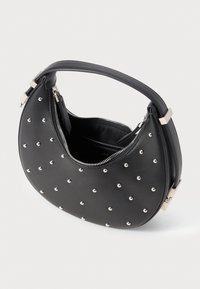 Musta nahk handbag, jossa on pyöristetty muoto, hopeiset niitit, vetoketjukiinnitys ja lyhyt kahva. Sisältä näyttää tilavalta ja vuoratussa.