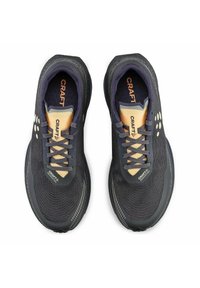 Baskets de sport noires avec un dessus en maille texturée, accents dorés, lacets et semelle en caoutchouc. Logo sur la languette et sur le côté, design épuré.