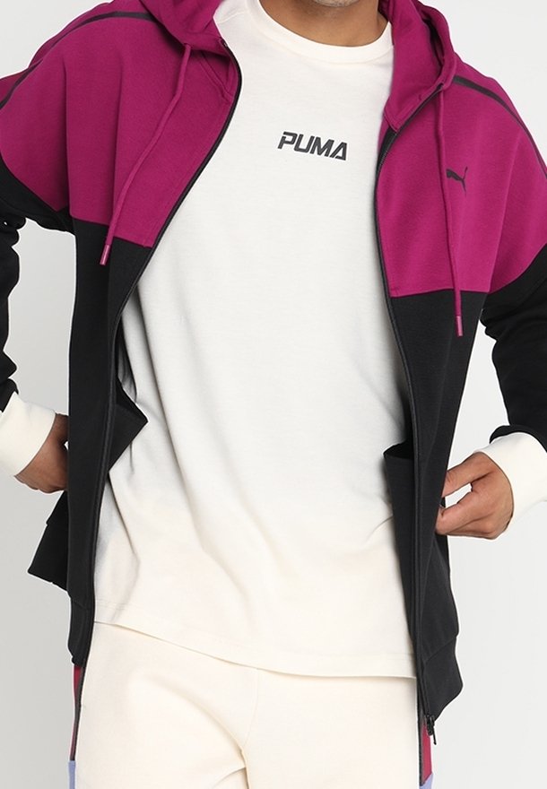 Haut de sweatshirt à fermeture éclair noir et magenta avec capuche, doté d'une poche kangourou, porté sur une chemise blanche avec le logo "PUMA" ; texture de tissu lisse.
