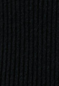 Schwarzer gerippter Stoff mit einer strukturierten Oberfläche. Vertikale Linien erzeugen Dimension. Das Material wirkt weich und dicht. Eine gleichmäßige Farbe über das gesamte Gewebe.
