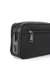 Custodia da viaggio in pelle nera con finitura texturizzata, doppie cerniere e un accento in hardware argento che presenta un logo del marchio e una porta elettronica.