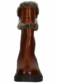 Botas de cuero marrón hasta el tobillo con un acabado suave, borde de piel sintética en la parte superior y una suela gruesa de goma negra. Presentan un cierre lateral.