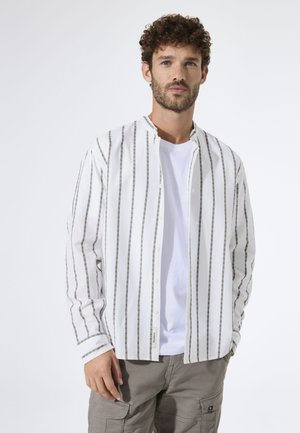 Weißes langärmeliges Hemd mit grauen vertikalen Streifen, geknöpftem Kragen und minimalistischem Design, kombiniert mit einem weißen T-Shirt und hellen Cargohosen.