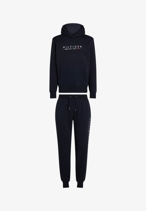 - Sweat-shirt à capuche bleu marine et pantalon de survêtement assorti. Comprend une poche avant, des poignets élastiques, et un branding en blanc, rouge et bleu sur le côté.