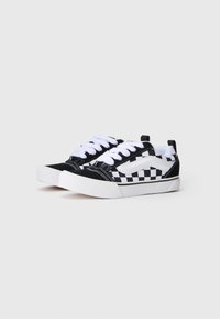 Svart og hvitt rutete lerret sneakers med hvite snørebånd, gummisåle og kontrasterende hvite sidelogoer. Lave sko med flat profil.