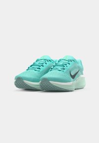 Light blue athletic shoes with a mesh upper, textured toe, and black logo. Features green accents and a cushioned sole for support.