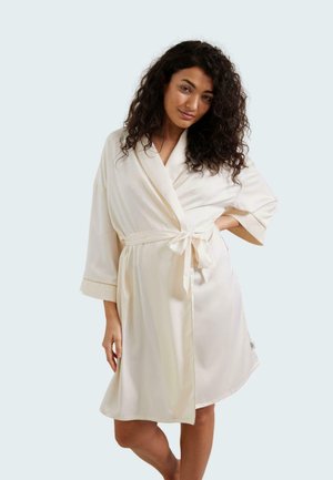Accappatoio di raso crema con maniche a tre quarti, vita legata e dettagli decorativi sui polsini. Texture liscia e design fluido.
