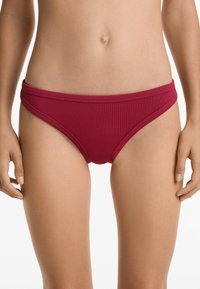 Rebrasto bikini dno v globoki burgundski barvi, ki ima nizko rez in ozki pas. Gladka tekstura brez vidnih kovinskih delov ali vzorcev.