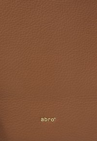 Brązowy skórzany portfel z teksturowaną powierzchnią i złotym logo "abro". Prosty design bez dodatkowych wzorów ani akcentów.
