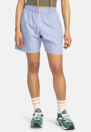Blauw-witte gestreepte shorts met een elastische tailleband, lichte stof en een relaxte pasvorm, gecombineerd met groene sneakers en witgestreepte sokken.