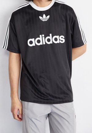 Zwart Adidas t-shirt met wit logo, korte mouwen en drie witte strepen op de schouders. Soepele stof met subtiele verticale textuur.