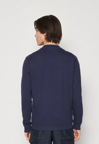 Felpa blu navy realizzata in tessuto misto cotone. Presenta un collo rotondo, maniche lunghe e polsini e orlo a coste. Design semplice e solido.