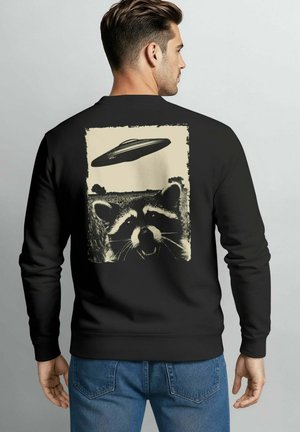 Schwarzer Sweatshirt mit einem abgenutzten Grafikdesign eines Waschbären und einer fliegenden Untertasse auf der Rückseite. Weiches Material mit gerippten Bündchen und Saum.