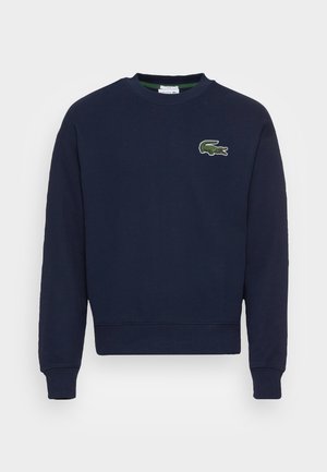 Sweat-shirt bleu marine à col rond avec manches longues et petit logo crocodile vert sur le côté gauche de la poitrine.