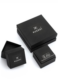 Svarta, matta askar i olika storlekar med "Kuzzoí"-logotyp på toppen. Tillverkade av återvunnet papper, med rena linjer och minimal design.