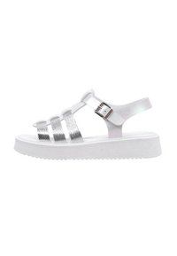 Sandalias de plataforma blancas con correas plateadas metálicas, que cuentan con un acabado texturizado y hebilla ajustable en el tobillo. Suela plana y estriada para mayor agarre.