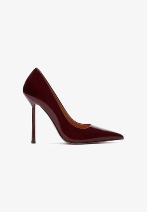 Burgundská lakovaná kožená lodička na vysokom opätku s špicatou špičkou a elegantným siluetou. Stiletto opätok s čiernym detailom na špičke. Hladká textúra.