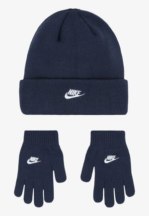Un bonnet en tricot bleu marine et des gants assortis, arborant un logo Nike blanc. Le bonnet a un revers replié ; les gants ont des poignets côtelés.
