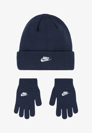 Gorro de malha azul-marinho e luvas combinando, apresentando um logo branco da Nike. O gorro tem uma aba dobrada; as luvas têm punhos canelados.