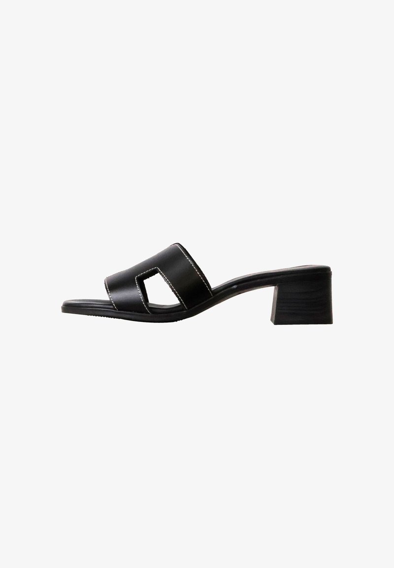 Sandale slide noire à bout ouvert avec un talon bloc bas et un détail de couture blanche sur la large bride en cuir.